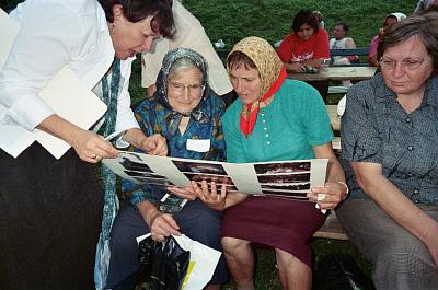 People at the festival reading greetings to them from people in Virginia, written on a poster-sized greeting card OR signing a poster-sized greeting card for us to take back to Virginia.
